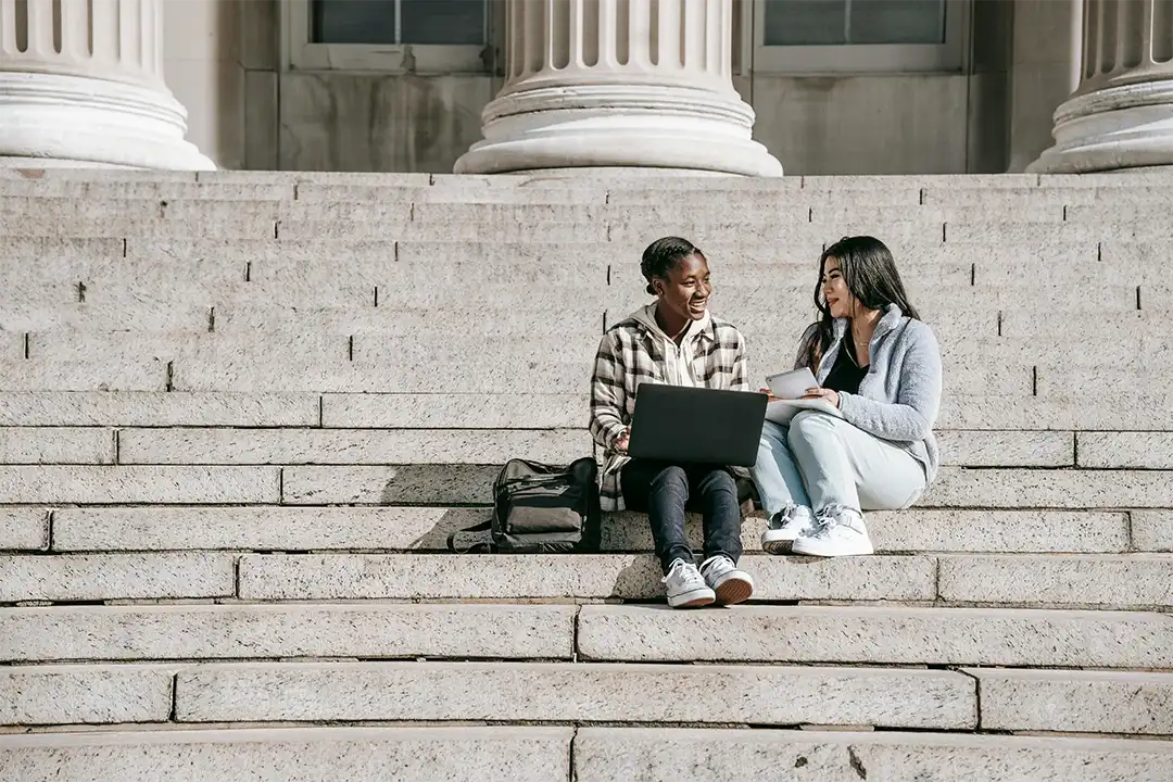Two students sitting on steps with coursework