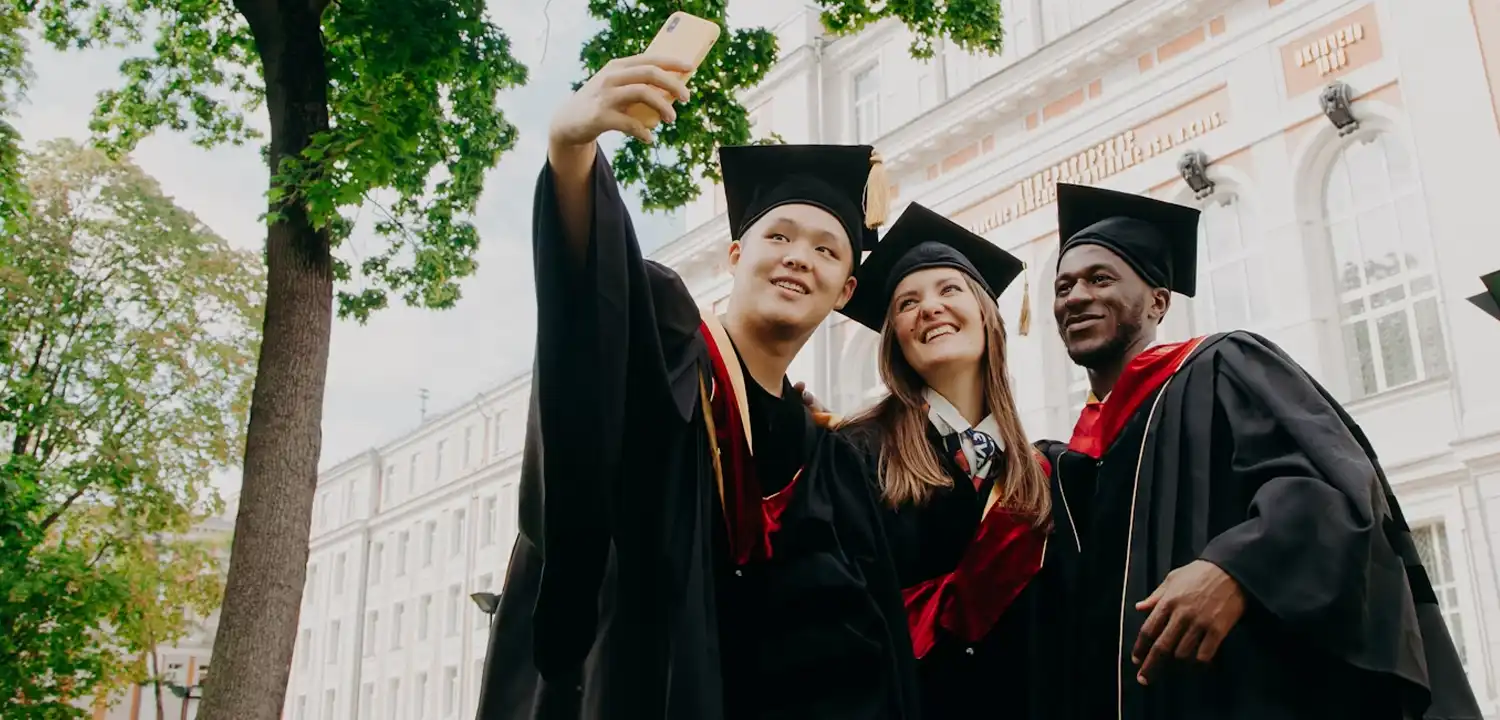 Three students wearing graduate gowns